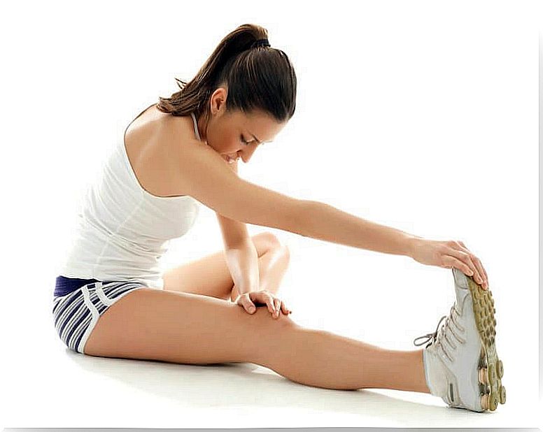 The woman stretches the muscles of her legs and back