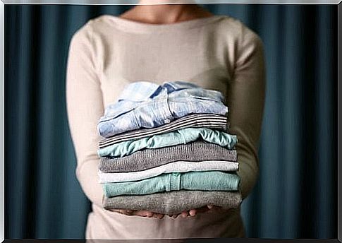 The woman is holding folded clothes