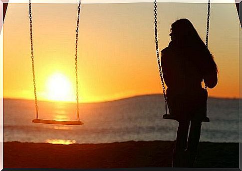 A woman sits on a swing - loneliness