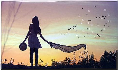 A woman is walking in a meadow at sunset